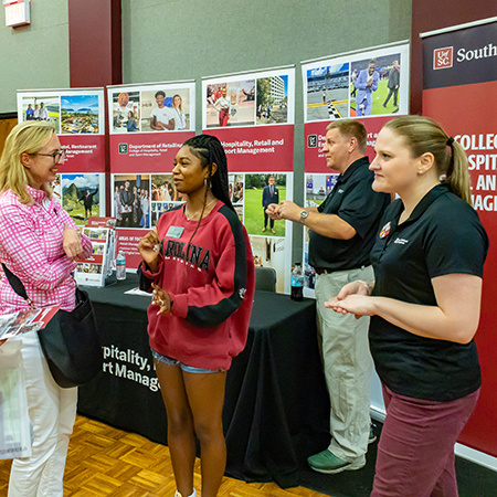 Collin Crick, Laura Nix and a member of the Leaders Program speak with prospective UofSC students at an Open House event.