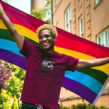 Student wearing a Gamecock t-shirt holding a pride flag.