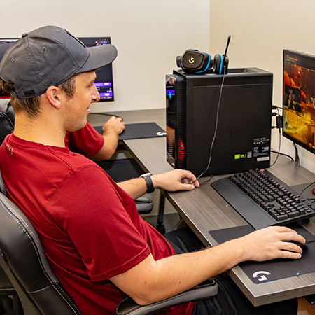 A student sits in front of a computer in the Esports Lab playing a video game.