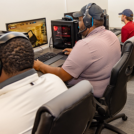 A student sits in front of a computer in the Esports Lab playing a video game.