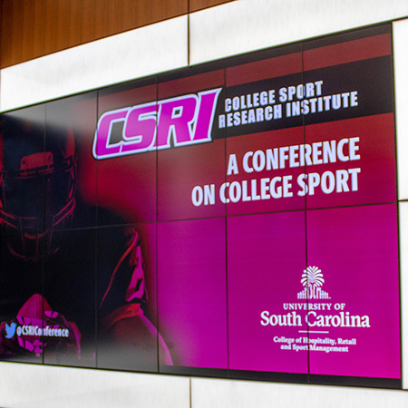A digital display showing the College Sport Research Institute, a conference on college sport.