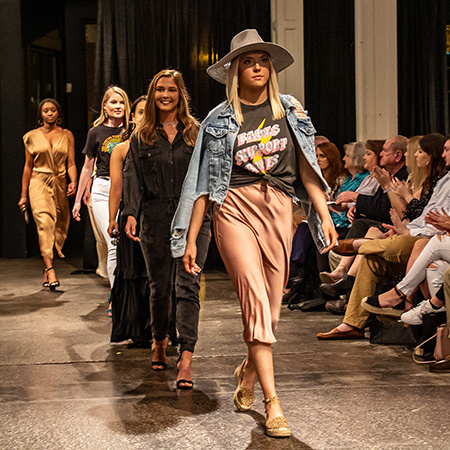 Members of USC's Fashion Board walk down the runway at a fashion show.