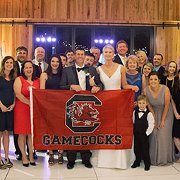 Lori Anna Varnadoe and Lee Davis with their wedding party. The bride and groom hold a Gamecock banner.
