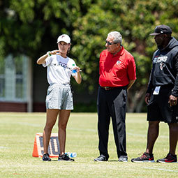 Kjahna O stands on a practice field with other Atlanta Falcons staff