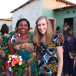 Amy Bardi, the founder of Clothed in Hope, stands with one of her students and several other colorfully dressed women at their graduation from the Clothed In Hope program in a village in Zambia..