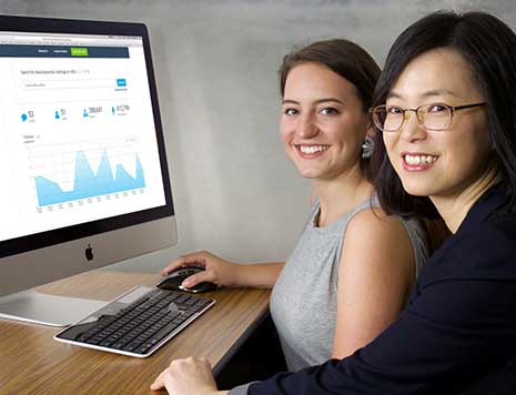 A student and faculty member pose with a computer demostrating the Keyhole platform