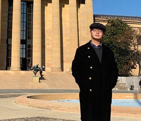 Guanlin Wu stands in front of the Philadelphia Museum of Art on a sunny blue-sky day