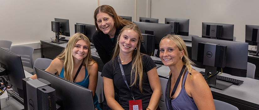 An HRSM advisor poses with three students at orientation