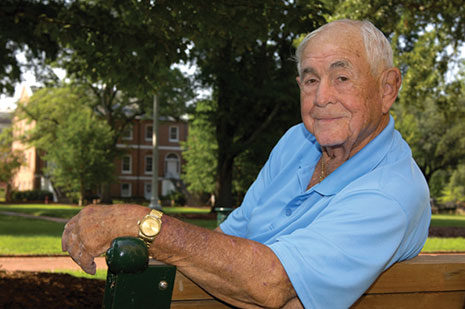 Harry E. Varney sits on a park bench amidst the UofSC Horseshoe green space.