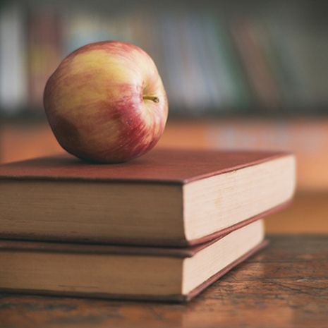 apple sitting on top of pile of books