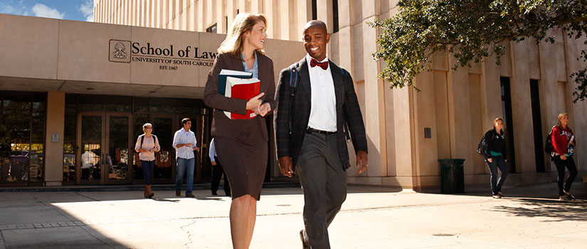 A white female student and black male student talk as they walk out of the doors of one of South Carolina Law's previous buildings.