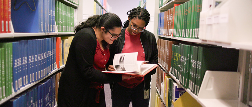 Students looking over a book at the library.