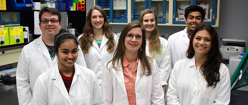 A smiling group of people in white coats. 