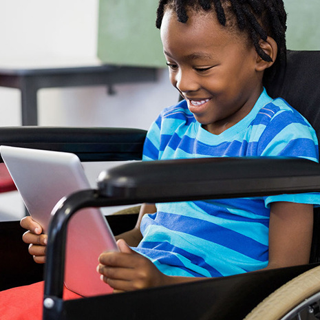 Young man in wheelchair smiles looking at tablet