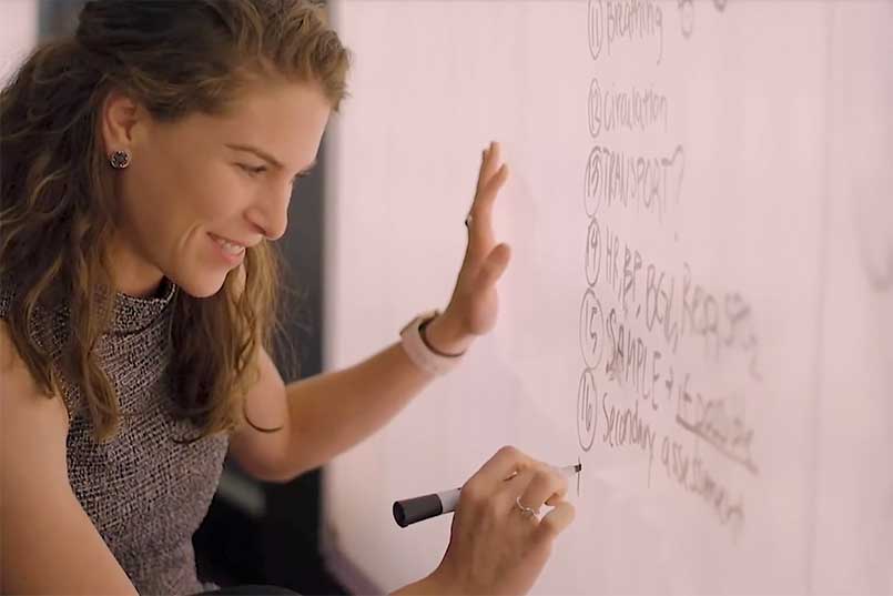 Female student writes on illuminated white board