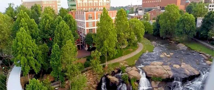 Aerial view of Greenville, SC showing buildings, river and waterfalls.