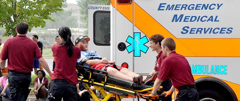 Student EMTs load a patient on a stretcher into an ambulance.