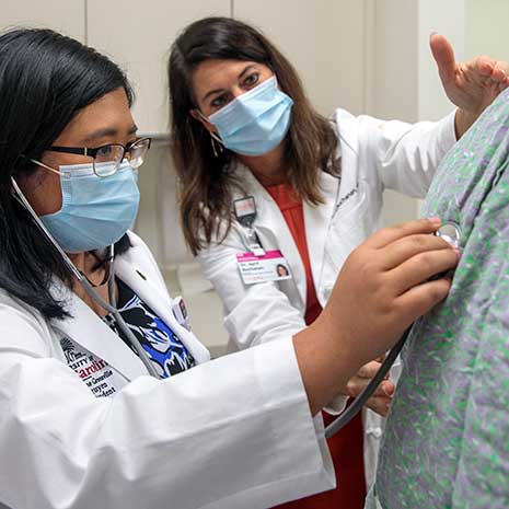 Doctor showing medical student the proper use of stethoscope on a patient.