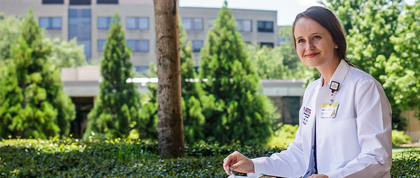 Photo of medical student in white coat outside of school building