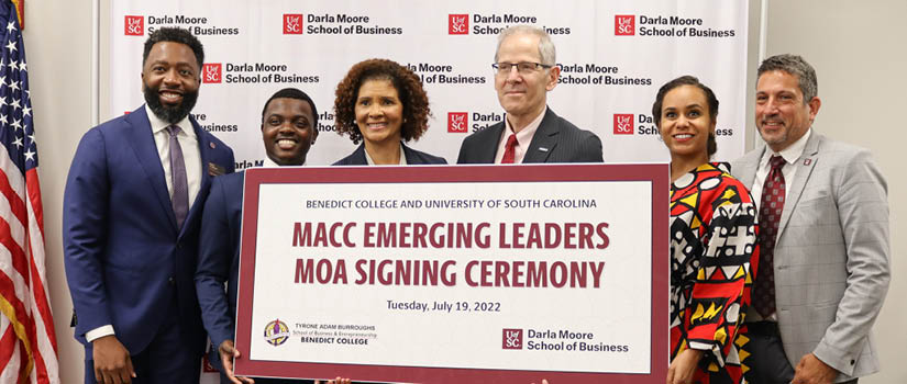 Image of UofSC's Julian Williams, Benedict College's Heyveon Clemons, Tracy Dunn and Moore School's Peter Brews, Tiara Dungy and Mark Cecchini holding the sign for the partnership celebration event