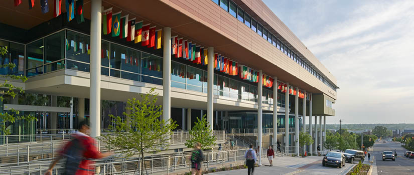 Image of the Moore School with the international flags and passersby in the foreground