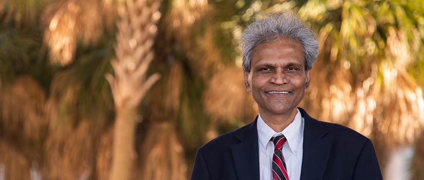 Image of Sanjay Ahire in the Moore School courtyard with the Palmetto Trees in the Background