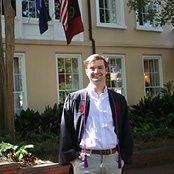 Image of Matt Hubbell in his graduation gown in front of the President's House