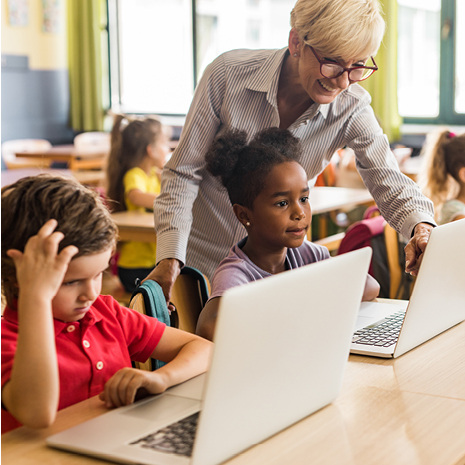 Teacher helping students on laptops