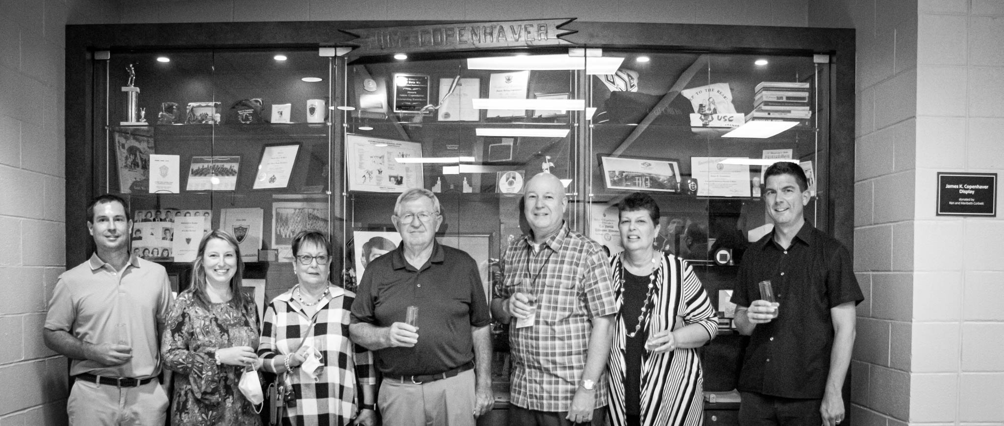 Ken Corbett stands with Director Cormac Cannon and the family of James K. Copenhaver in front of the display case 