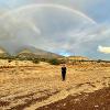 Woman standing under a rainbow in a field