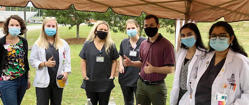Group of students and pharmacists under a tent
