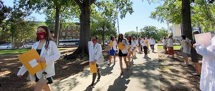 Students in white coats and masks
