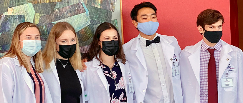 Group of students in white lab coats and face masks
