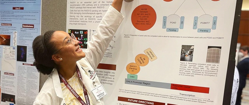 Student in front of research poster