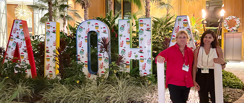 Graduate student and faculty member in front of "Aloha" signage