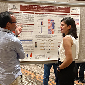 Sana speaking with audience member in front of research poster