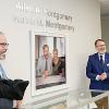 COMD Chair Kenn Apel (left) and Arnold School Dean Thomas Chandler unveil the portrait of Al and Marcia Montgomery, for whom the clinic has been named. 