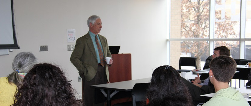 Man standing at the front of a classroom speaking to others