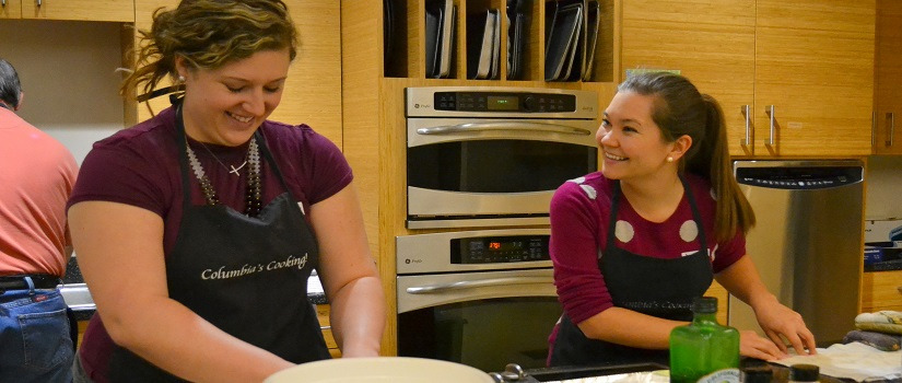 Two young people smiling at each other while preparing food