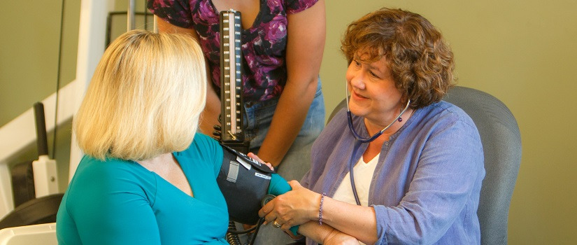 Woman taking blood pressure of a patient