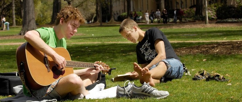 Student playing a guitar in the park