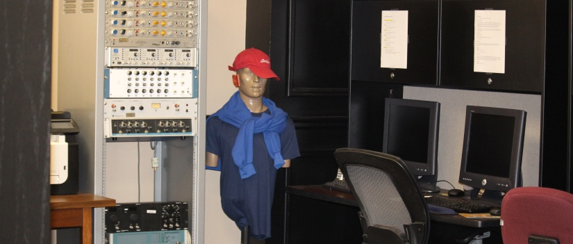 Communication Sciences and Disorders office with computers and a mannequin wearing a hat
