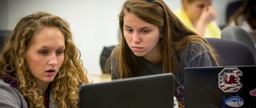 Two undergraduate students looking at a computer in class