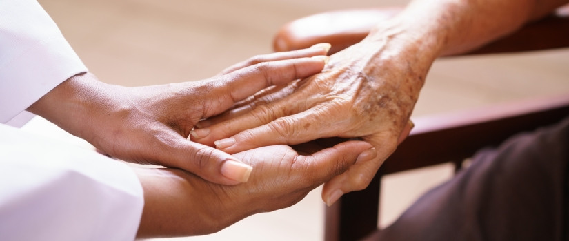 Young person holding the hand of an elderly individual