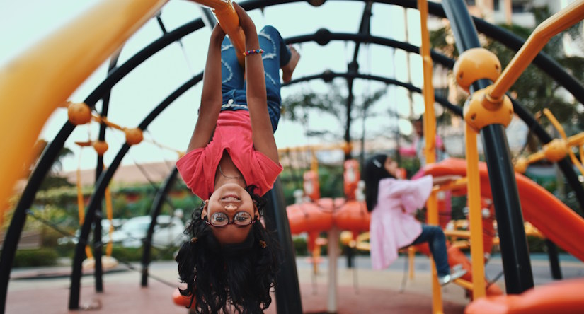 girl hanging upside down on playground