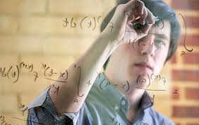 Man writing math equations on a piece of glass