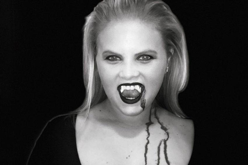 Black and white photo of a girl dressed as a vampire showing her fangs.