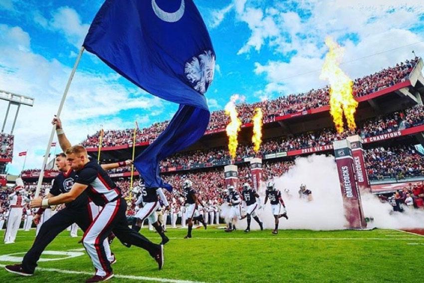 Cheerleaders running with a South Carolina flag on the field before a football game. 
