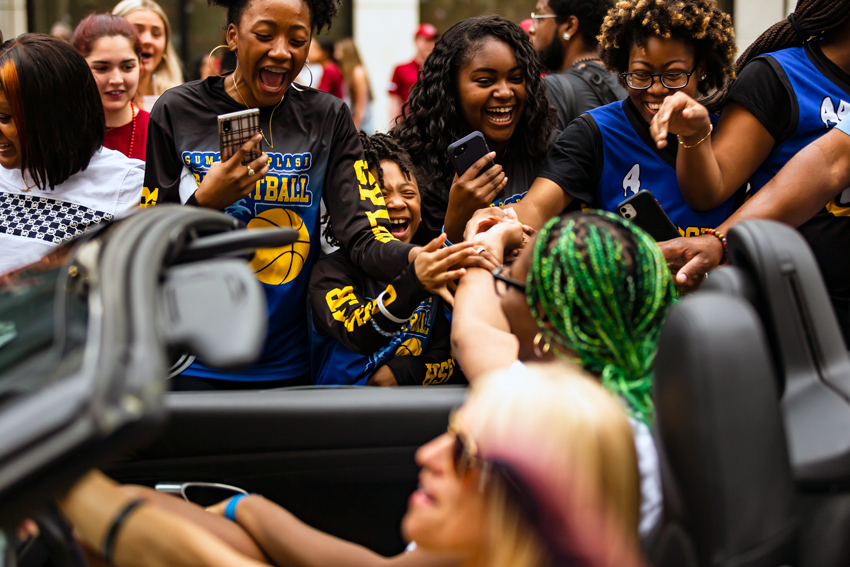 Young basketball fans reach out for Aliyah Boston's hand as she rides by in a convertible during the 2022 championship parade. 