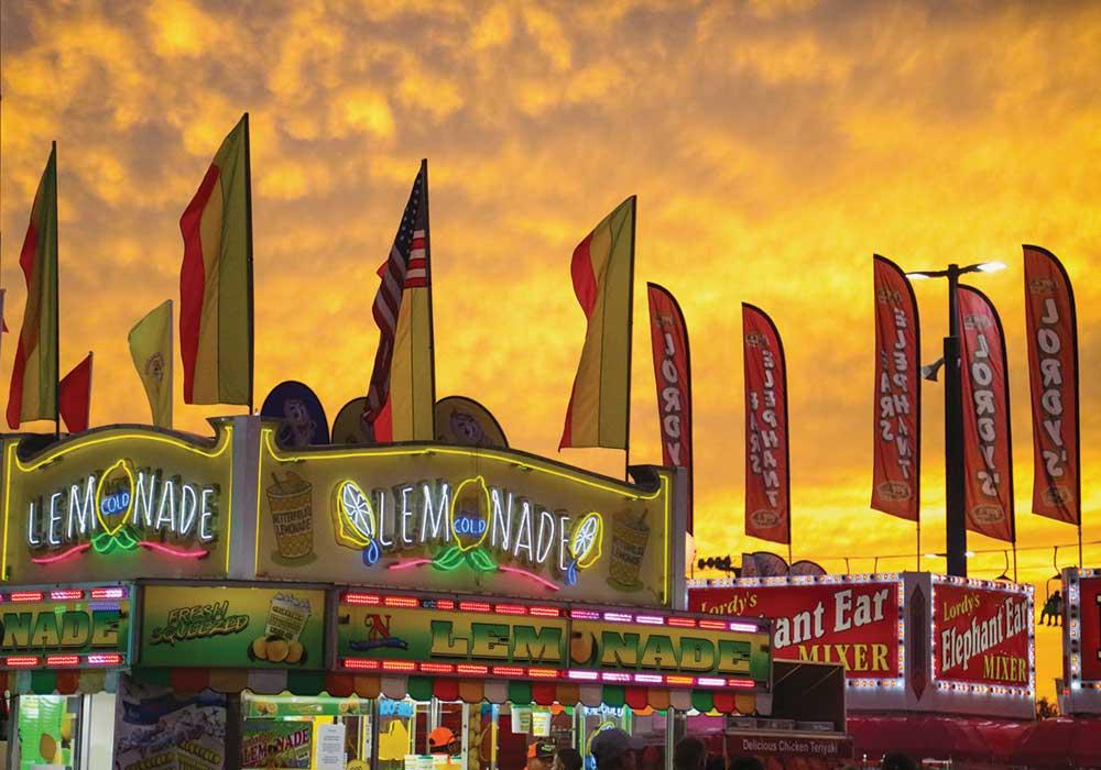 A yellow sunset with lemonde stand in the foreground at the SC State Fair.